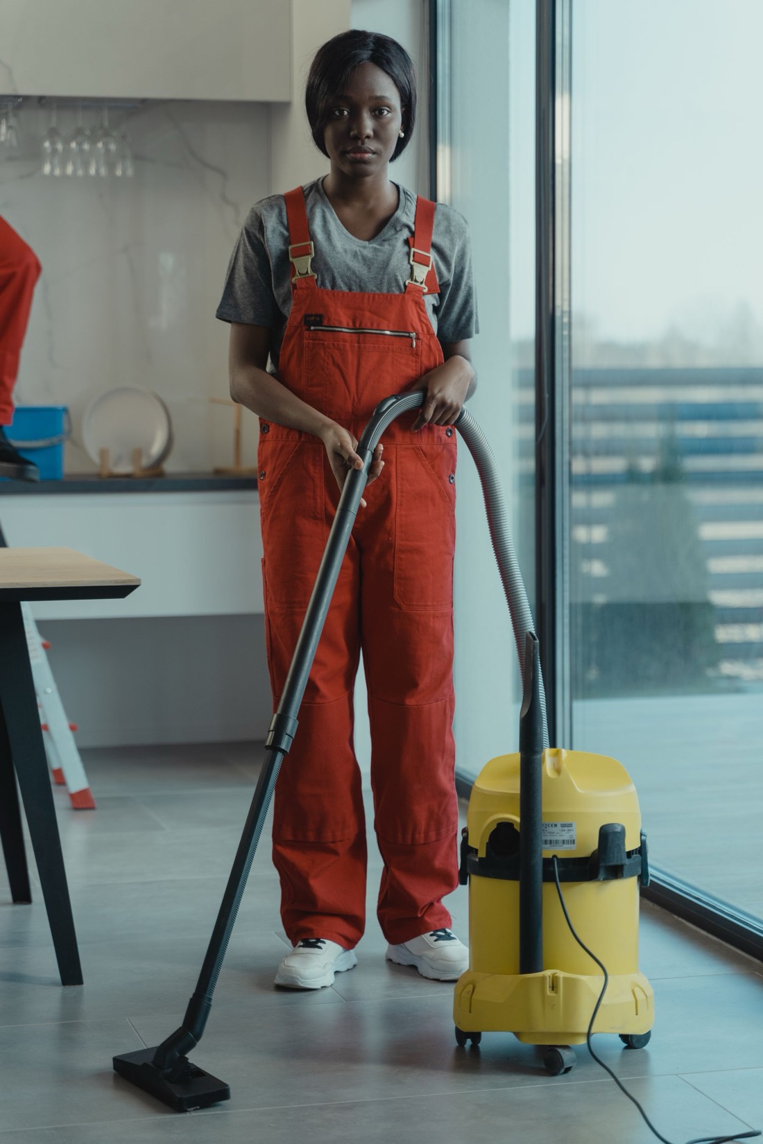 Agente en combinaison passant l'aspirateur dans un local lumineux