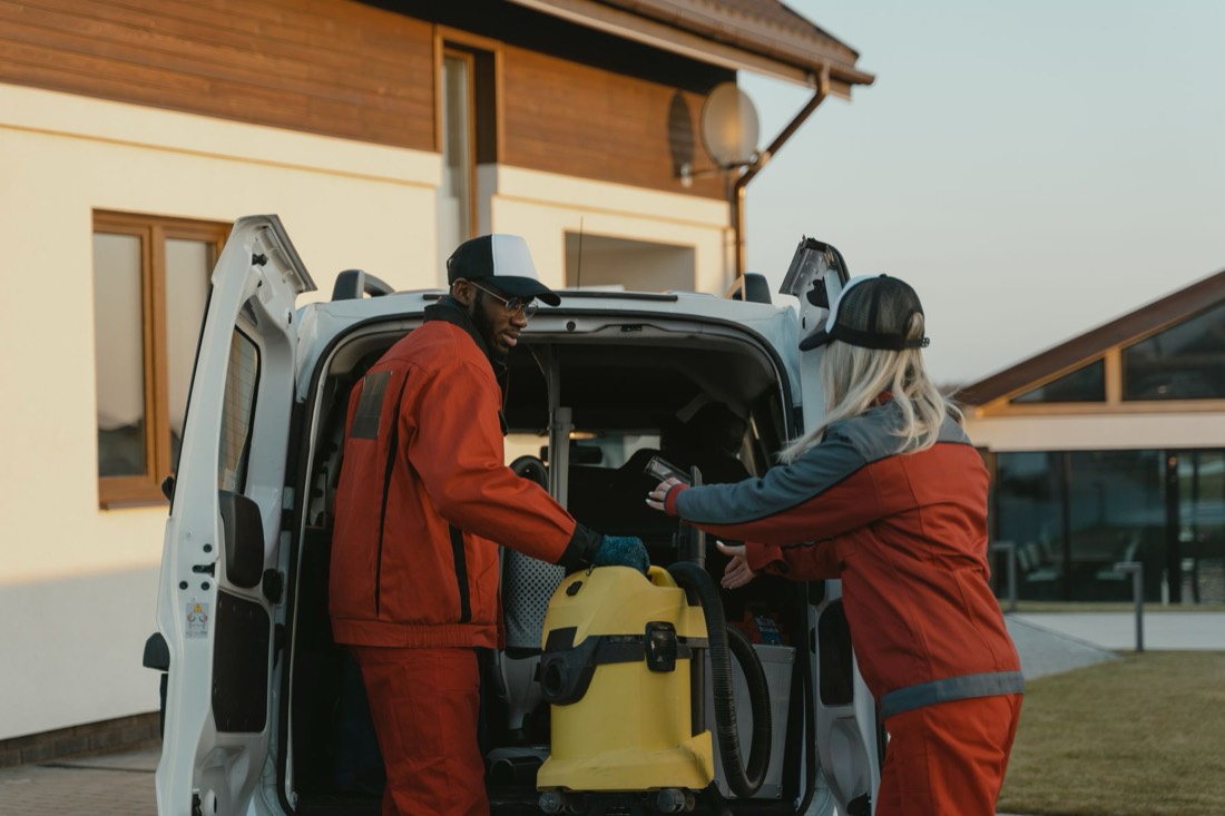 Deux agents chargent un aspirateur dans une camionnette